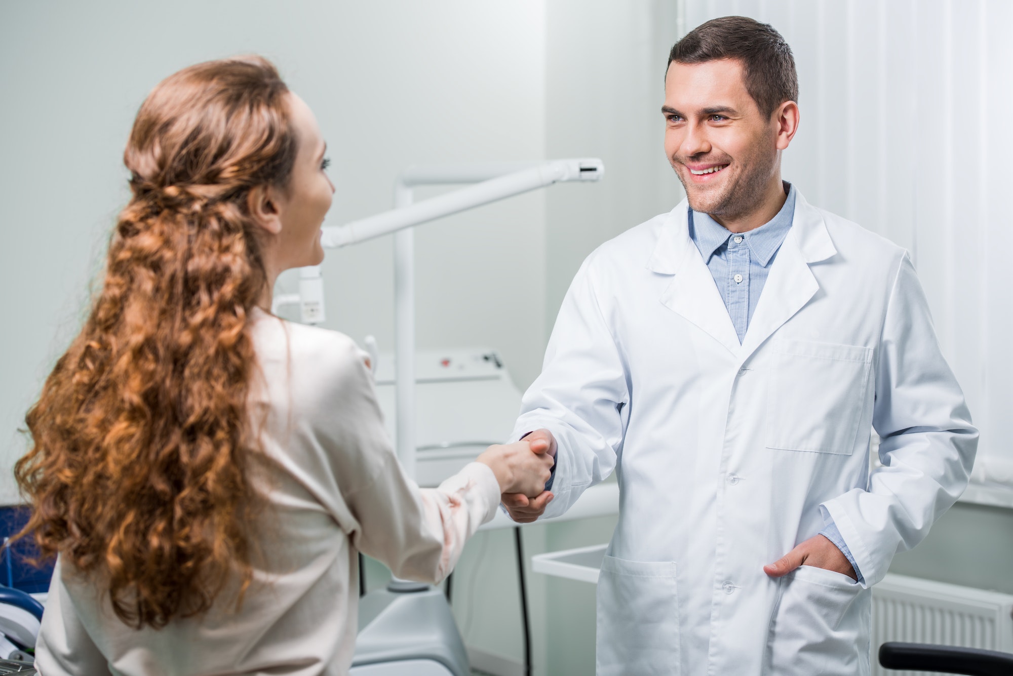 woman shaking hands with dentist standing with hand in pocket